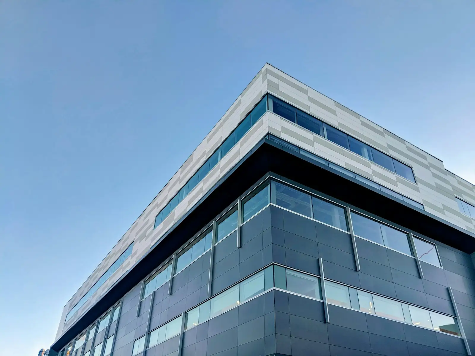 Modern glass and steel office building against a blue sky